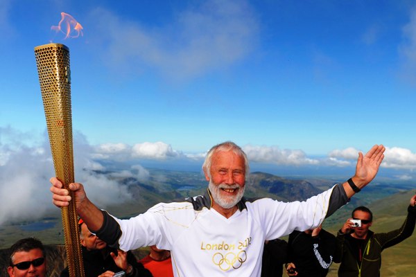 British mountaineer Chris Bonnington holds the Olympic flame on top of Snowdon, the highest peak in Wales, in Snowdonia National Park, Wales May 29, 2012. The flame was carried through Wales on day 11 of the Torch Relay, as part of the London 2012 Olympic Games. REUTERS/LOCOG/Handout (BRITAIN - Tags: SPORT OLYMPICS SOCIETY) NO SALES. NO ARCHIVES. FOR EDITORIAL USE ONLY. NOT FOR SALE FOR MARKETING OR ADVERTISING CAMPAIGNS. THIS IMAGE HAS BEEN SUPPLIED BY A THIRD PARTY. IT IS DISTRIBUTED, EXACTLY AS RECEIVED BY REUTERS, AS A SERVICE TO CLIENTS