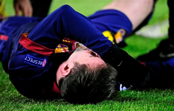 El jugador argentino del Barcelona, Lionel Messi, hace gestos de dolor tras sufrir una lesión en la rodilla izquierda en un partido contra Benfica por la Liga de Campeones el miércoles, 5 de diciembre de 2012, en Barcelona. (AP Photo/Manu Fernandez)