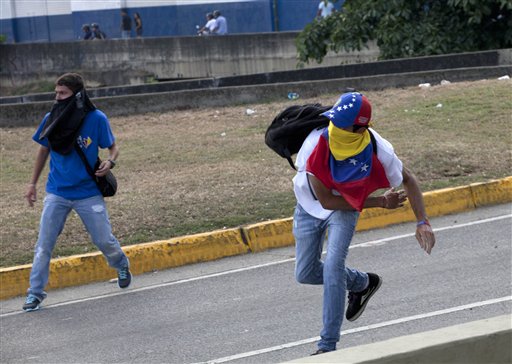 Manifestantes lanzan piedras contra la policía antidisturbios en medio de enfrentamientos entre opositores y estudiantes con las autoridades que dispersaron una protesta que bloqueaba una autopista en el barrio de Altamira, Caracas, Venezuela, el lunes 15 de abril del 2013. Las tropas de la Guardia Nacional dispersaron a quienes protestaban por los resultados de la elección presidencial especial del domingo, cuyos estrechos resultados a favor del oficialista Nicolás Maduro fueron rechazados por el candidato opositor Henrique Capriles, quien demandó un conteo de todos los votos. (AP Foto/Ramon Espinosa)