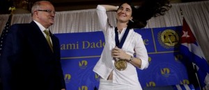La bloguera y activista cubana Yoani Sánchez, derecha, se ajusta el cabello tras recibir una medalla de manos de Eduardo Padrón, izquierda, presidente del Miami Dade College, después de hablar en la Freedom Tower de esa universidad, el lunes 1 de abril de 2013, en Miami. (Foto AP/Lynne Sladky)
