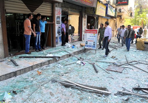 Agentes de la policía conversan con los propietarios de establecimientos comerciales cerca de donde estalló una poderosa bomba en el distrito de Marjeh, en el centro de Damasco, Siria, el martes 30 de abril de 2013. Al menos 13 personas murieron y 70 resultaron heridas en el atentado, según las autoridades. (AP Foto/SANA)