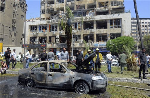 Personal de seguridad inspecciona un automóvil incendiado en el lugar donde estalló una poderosa bomba en el distrito de Marjeh, en el centro de Damasco, Siria, el martes 30 de abril de 2013. Al menos 13 personas murieron y 70 resultaron heridas en el atentado, según las autoridades. (AP Foto/SANA)