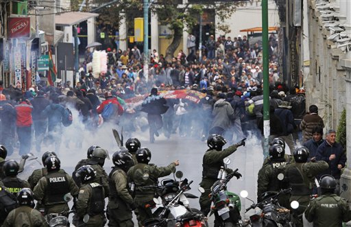 Manifestantes huyen ante los efectos de las bombas lacrimógenas lanzadas por la policía durante una marcha de mineros que protestan en La Paz, Bolivia, el jueves 16 de mayo de 2013. (AP Photo/Juan Karita)