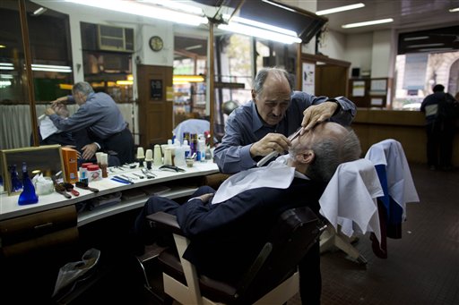 al barbero Mario Saliche atendiendo a un cliente en la peluquería donde el papa Francisco se cortaba el pelo en Buenos Aires, Argentina