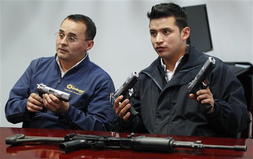 En esta fotografía del 29 de abril de 2013, Javier Farigua, a la izquierda, y Edward López, sostienen prototipos de la nueva pistola "Córdova" producida por la estatal Industria Militar en Soacha, Colombia. La pistola 9 milímetros saldrá al mercado en los primeros días de junio. (AP foto/Fernando Vergara)
