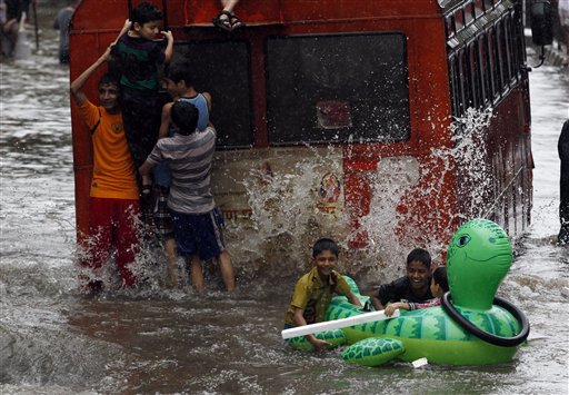 Niños juegan con un inflable en una calle inundada por las lluvias torrenciales en Mumbai, India, el domingo 16 de junio de 2013. Las inundaciones han dejado unas dos decenas de muertos, informó el gobierno el lunes. (Foto AP/Rajanish Kakade)
