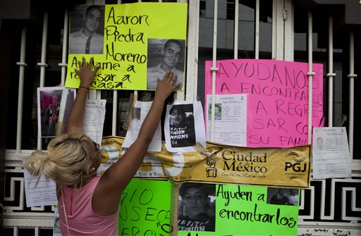 Una mujer coloca fotos en la entrada de un bar donde se produjo un secuestro masivo en la Ciudad de México, el 30 de mayo del 2013 (AP Foto/Eduardo Verdugo)