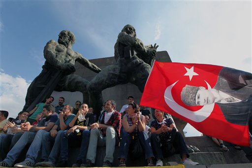 Manifestantes turcos con una banderola con la imagen del fundador del país, Kemal Ataturk, reunidos en la Plaza Kizilay en Ankara, la capital, el sábado 8 de junio de 2013. El primer ministro Recep Tayyip Erdogan se reunió el sábado con los líderes de su partido en momentos que las protestas contra el gobierno entran en su noveno día y miles de personas siguen ocupando la central Plaza Taksim en Estambul. (Foto AP/Burhan Ozbilici)