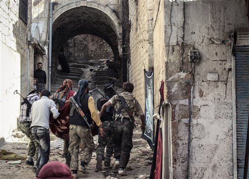 Un grupo de rebeldes del Ejército Sirio Libre cargan a un camarada herido en el pueblo de Harem, Siria, (Foto AP/Mustafa Karali, Archivo)