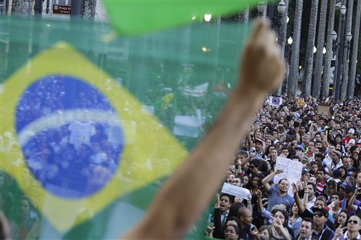 Un manifestante sostiene la bandera brasileña frente a una multitud congregada en la principal plaza de Sao Paulo, Brasil, el martes 18 de junio de 2013. (Foto AP/Nelson Antoine)