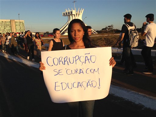 Caroline Moura posa para una foto mientras sostiene un cartel en el que se lee en portugués “la corrupción se cura con educación”, durante una protesta contra el gobierno en Brasilia.