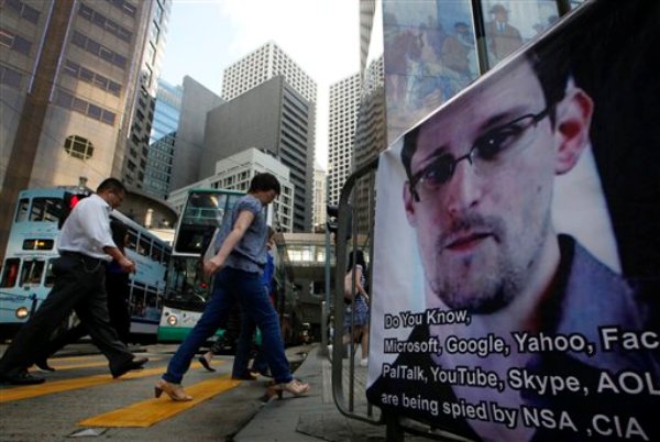 Los peatones pasan frente a un cartelón con la imagen de Edsard Snowden, que reveló planes secretos de espionaje en Estados Unidos, por el distrito comercial de Hong Kong el 17 de junio del 2013 (AP Foto/Kin Cheung)