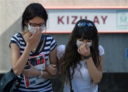 Dos turcas sufren los efectos de los gases lacrimógenos en la Plaza Kizilay, cerca de la oficina del primer ministro Recep Tayyip Erdogan, en Ankara el martes, 4 de junio del 2013. Las protestas contra el dirigente islámico han aumentado en todo el país, especialmente en Estambul. (Foto AP/Burhan Ozbilici)