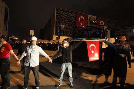 Manifestantes forman una cadena humana frente a elementos de la policía en plaza Taksim de Estambul la noche del miércoles 12 de junio de 2013. (Foto AP/Thanassis Stavrakis)