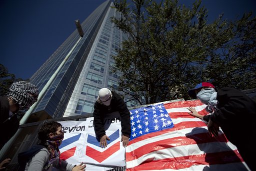 Manifestantes colocan el logotipo de la petrolera Chevron sobre una bandera de Estados Unidos durante una protesta contra un acuerdo entre el ente estatal YPF argentino y la petrolera estadounidense en las afueras de las oficinas centrales de YPF en Buenos Aires, Argentina, el martes 16 de julio de 2013. (AP Photo/Victor R. Caivano)