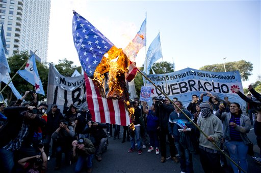 Manifestantes queman una bandera de Estados Unidos durante una protesta contra un acuerdo entre el ente estatal YPF argentino y la petrolera estadounidense Chevron en las afueras de las oficinas centrales de YPF en Buenos Aires, Argentina, el martes 16 de julio de 2013. (AP Photo/Victor R. Caivano)