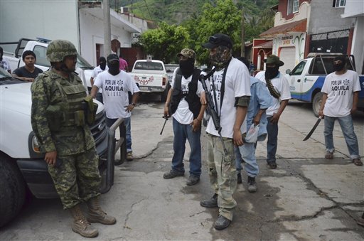 Un soldado del ejército mexicano habla con hombres armados de un grupo de autodefensa en el poblado de Aquila, Michoacán, el miércoles 24 de julio de 2013.