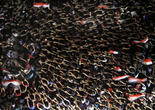 Manifestantes egipcios alzan sus manos y sostienen banderas nacionales durante las protestas en contra del presidente Mohammed Morsi en la Plaza Tahrir, el punto neurálgico de las revueltas en El Cairo, Egipto, el viernes 28 de junio de 2013. Se espera que miles de detractores y partidarios de Morsi participen en las marchas multitudinarias del sábado luego de una violenta serie de enfrentamientos entre ambos bandos que ha dejado al menos siete muertos. (Foto AP/Amr Nabil)