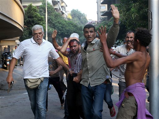Opositores del derrocado presidente egipcio Mohamed Morsi detienen a un presunto partidario del ex mandatario que resultó herido en enfrentamientos en El Cairo, Egipto, el lunes 22 de julio de 2013. (Foto AP/Hussein Malla)