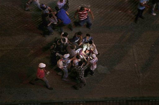 Personas transportan a dos lesionados durante enfrentamientos entre partidarios y oponentes del depuesto mandatario islamista de Egipto, Mohammed Morsi, que estallaron en El Cairo, Egipto, el viernes 5 de julio de 2013. (AP Foto/Hassan Ammar)