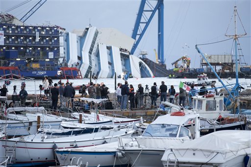 Un grupo de reporteros observan al crucero Costa Concordia ladeado en aguas de la isla toscana de Giglio, Italia, el lunes 16 de septiembre de 2013. (Foto AP/Andrew Medichini)