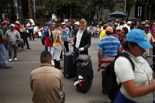 Un hombre con maletas se abre paso a través de un grupo de manifestantes rumbo a un hotel en la Avenida Paseo de la Reforma en la Ciudad de México, el miércoles 4 de septiembre de 2013. Maestros huelgistas continuaron su protesta contra la reforma educativa después de que el Senado la aprobó. (Foto AP/Iván Pierre Aguirre)