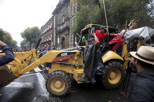 Maestros huelguistas movilizan una excavadora para levantar barricadas ante un posible enfrentamiento con la policía en la Ciudad de México, el viernes 13 de septiembre de 2013. (AP Foto/Eduardo Verdugo)