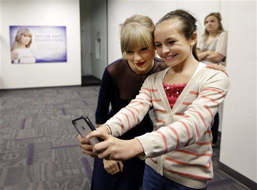 Taylor Swift posa para un retrato con Piper Moralez, de 11 años, en el Museo y Salón de la Fama de la Música Country el sábado 12 de octubre de  2013, en Nashville, Tenesí. Swift inauguró en el museo el Centro Educativo Taylor Swift cuyo costo fue de 4 millones de dólares. (Foto AP/Mark Humphrey)