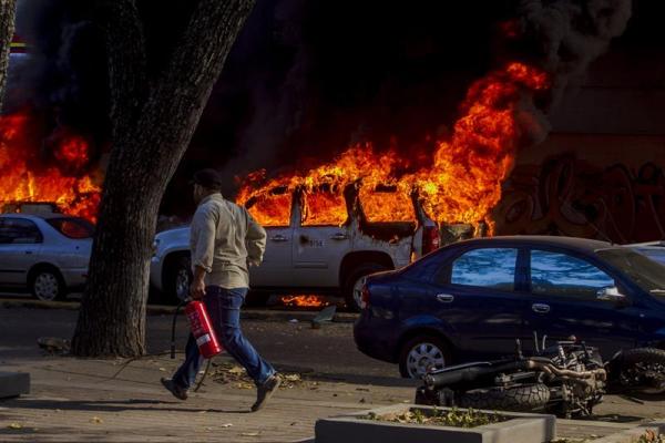Foto: una persona camina con un extintor cerca a un vehículo incendiado hoy, miércoles 12 de febrero de 2014, durante una marcha convocada por la oposición, en Caracas (Venezuela). EFE/Miguel Gutiérrez