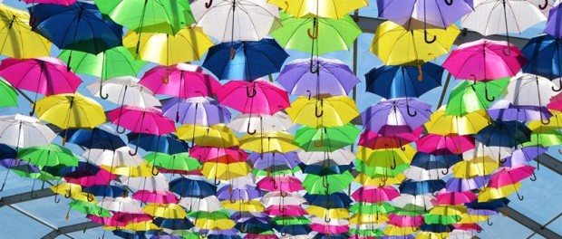 Fotografía facilitada por la empresa Sextafeira, de una calle de la pequeña localidad de Águeda, invadida de color en forma de paraguas flotantes.
