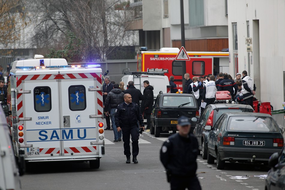 Agentes de policía y bomberos reunidos ante la sede del periódico satírico Charlie Hebdo en París, el 7 de enero de 2015. Once personas murieron en un ataque contra la sede del medio, según la policía. (AP Foto/Thibault Camus)