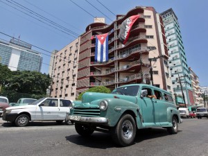 Un auto pasa frente a un edificio donde se expone la bandera cubana y la del movimiento del 26 julio hoy, martes 21 de julio de 2015, en La Habana (Cuba), un día después de la apertura de la Embajada de estados Unidos en la Isla. EFE/Ernesto Mastrascusa