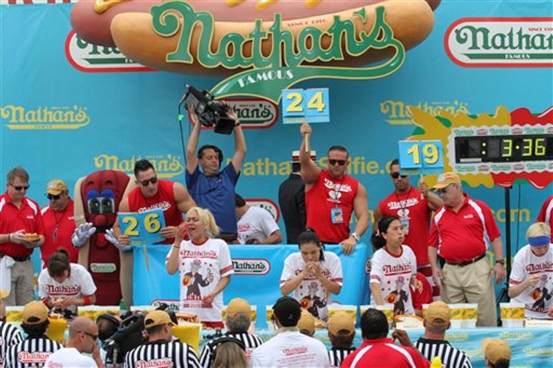 Miki Sudo, 2da izquierda, y Sonya "Viuda Negra" Thomas, centro, participan en el concurso de comer hot dogs en la playa neoyorquina de Coney Island, parte de los festejos tradicionales del Día de la Independencia de Estados Unidos, sábado 4 de julio de 2015. Sudo se impuso con 38 salchichas.  (AP Foto/Tina Fineberg)