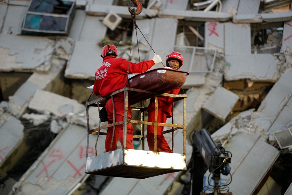 Dos socorristas transportan a una víctima retirada de entre los restos de un edificio de apartamentos en Tainan, Taiwán, el domingo 7 de febrero de 2016. Los socorristas detectaron el domingo señales de vida entre los restos del inmueble que se vino abajo durante un poderoso sismo que dejó el día anterior al menos 32 muertos y centenares de heridos en el sur de Taiwán. (AP Foto/Wally Santana)