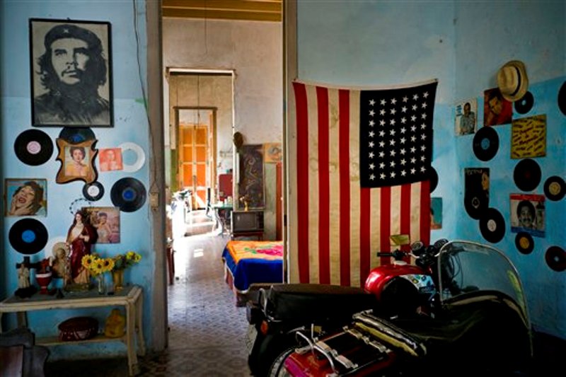 Una foto del revolucionario Ernesto "Che" Guevara está en una pared y en la otra  hay bandera de EEUU en una vivienda en La Habana, Cuba, el martes 15 de marzo de 2016. Cinco días antes de que se realice el primer viaje de un presidente de EEUU a La Habana en casi 90 años, el gobierno de Barack Obama le propinó una serie de golpes al embargo comercial a Cuba al convertir la prohibición de viajar a la isla en un sistema que depende de que las personas digan que el propósito de que su viaje es educativo, y no turístico, y al allanar el camino para que jugadores de béisbol, y otros atletas profesionales, puedan algún día jugar en las Grandes Ligas o en otras ligas profesionales estadounidenses. (Foto AP / Ramón Espinosa)