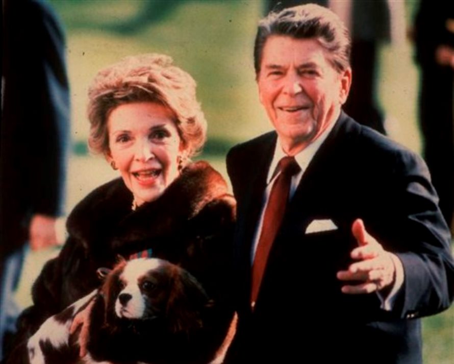 En esta imagen de archivo, tomada en diciembre de 1986, la primera dama de Estados Unidos Nancy Reagan sostiene a la mascota de la familia, Rex, mientras camina junto a su esposo Reagan por el jardín sur de la Casa Blanca. (Foto AP/Dennis Cook, archivo)