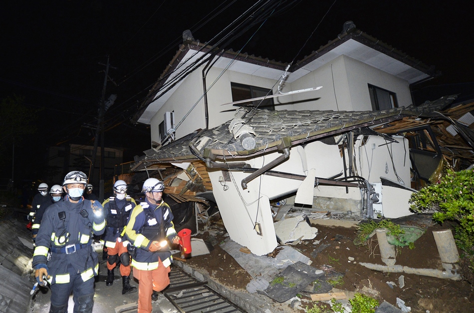 Bomberos revisan los daños en una casa colapsada en Mashiki, cerca de la ciudad de Kumamoto, en el sur de Japón, luego de un terremoto la mañana del viernes 15 de abril de 2016. Los rescatistas en el sur de Japón buscaban a residentes atrapados entre los escombros de al menos una docena de casas que colapsaron luego de que el potente terremoto de magnitud 65 azotara el jueves con tal fuerza que interrumpió los servcios de agua y electricidad. (Tomoaki Ito/Kyodo News via AP)