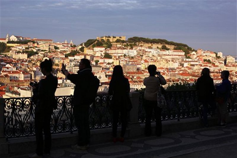 En la imagen, la silueta de varios turistas haciendo fotos al centro de Lisboa al sol del atardecer. (AP Foto/Armando Franca)