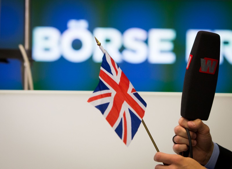 El presentador de un programa de noticias financieras sostiene una bandera británica mientras informa desde la Bolsa de Fráncfort, Alemania, el viernes 24 de junio de 2016. (Frank Rumpenhorst/dpa via AP)