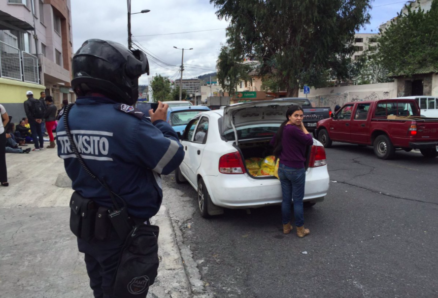 Oficial de la Policía fotografiando a mujer que fue a donar comida a familiares de cubanos detenidos en Hotel Carrión. Foto de Daniela Salazar.
