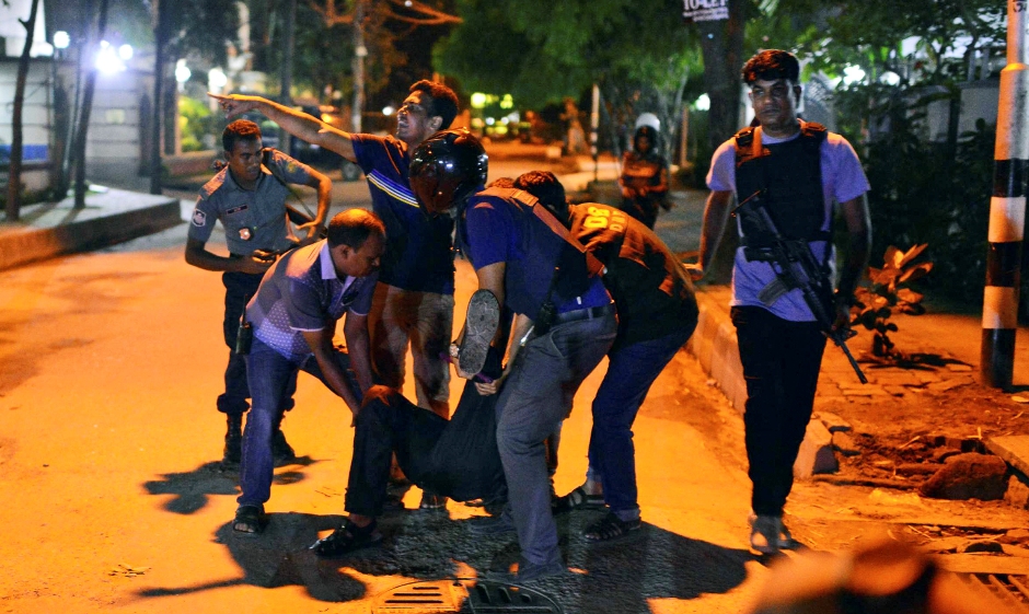 Un grupo de personas ayudan a un herido después que hombres armados atacaron un restaurante popular entre los extranjeros en una zona diplomática de Daca, la capital de Bangladesh, el viernes 1 de julio de 2016, donde tomaron rehenes e intercambiaron disparos con fuerzas de seguridad. (AP Foto)