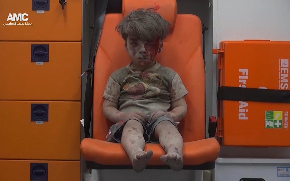 En esta imagen, tomada de un video distribuido por el grupo opositor sirio Aleppo Media Center (AMC), aparece un niño sentado en una ambulancia tras ser rescatado de entre los escombros de un edificio alcanzado por un bombardeo aéreo en Alepo, Siria, el 17 de agosto de 2016. (Aleppo Media Center via AP)