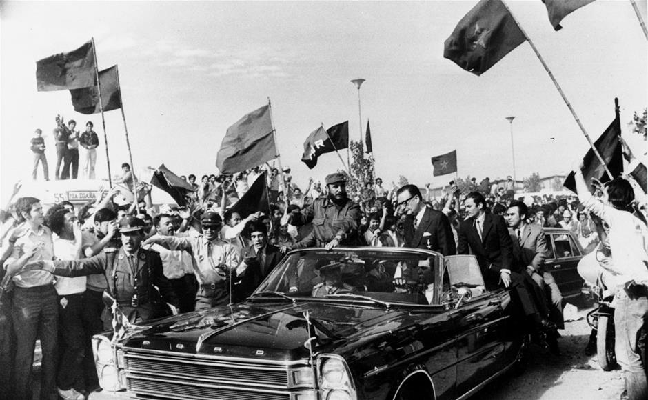 En esta fotografía del 10 de noviembre de 1971, el líder cubano Fidel Castro, centro izquierda, viaja acompañado por el presidente chileno Salvador Allende entre una multitud que ondea banderas comunistas en Santiago, Chile. Fidel Castro falleció el 25 de noviembre de 2016 a los 90 años. (Foto AP/Archivo)