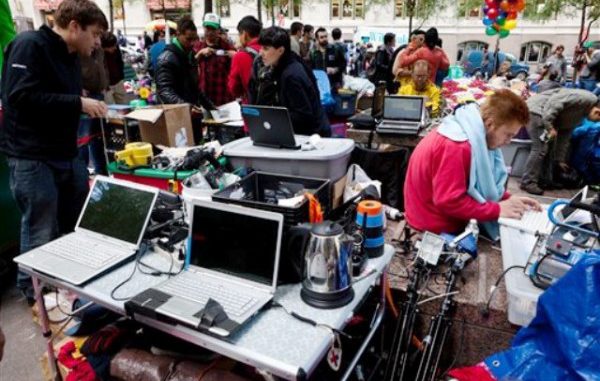 Los manifestantes del grupo Occupy Wall Street que han acampado durante más de dos semanas en el Distrito Financiero de Nueva York tienen un área de medios donde actualizan las noticias en computadoras portátiles alimentadas por energía de generadores a base de gas el domingo 2 de octubre de 2011. (Foto AP/John Minchillo)
