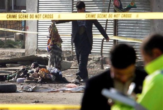 Integrantes del equipo de peritos de las autoridades afganas, derecha, recaban información mientras un hombre apila objetos en el lugar donde se llevó a cabo un ataque suicida en Kabul, Afganistán, el martes 6 de diciembre de 2011. (Foto AP/Musadeq Sadeq)