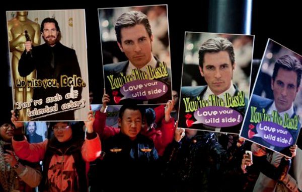 Admiradores chinos sostienen imágenes del actor inglés Christian Bale mientras lo esperan en la alfombra roja de un evento promocional de la nueva película de Zhang Yimou, "The Flowers of War", el lunes 12 de diciembre del 2011 en Beijing. (AP Foto/Andy Wong)