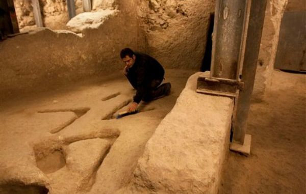 En esta foto del 1 de diciembre del 2011, el arqueólogo Eli Shukron, de la Autoridad de Antigüedades de Israel, examina tallas en piedra que datan de hace miles de años y que fueron descubiertas en una excavación en Jerusalén (AP Foto/Sebastian Scheiner)