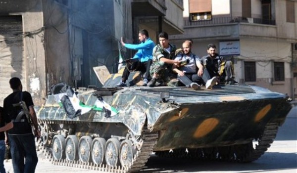 Soldados y rebeldes descansan juntos sobre un tanque de guerra blindado poco después de que los soldados del ejército sirio desertaron de las fuerzas del gobierno, en el distrito de Khaldiyeh, en la provincoa de Homs del centro de Siria, el sábado 12 de mayo de 2012. Las fuerzas sirias mataron al menos a cinco personas el domingo 13 de mayo en una redada en una villa agrícola del noroeste de Siria. (Foto AP/Fadi Zaidan)