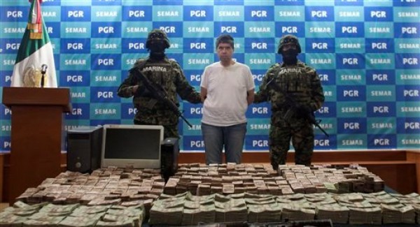 Infantes de la Marina mexicana muestran a los medios a Eric Jovan Lozano Díaz, alias "Cucho", un presunto operador financiero del cartel de las drogas de Los Zetas, el viernes 15 de junio de 2012 en Ciudad de México. Lozano fue detenido en la ciudad fronteriza norteña de Nuevo Laredo en poder de poco más de 41 millones de pesos (equivalente a unos 2,9 millones de dólares) y más de un millón de dólares, todo en efectivo, informó la dependencia. (AP Foto/Alexandre Meneghini)