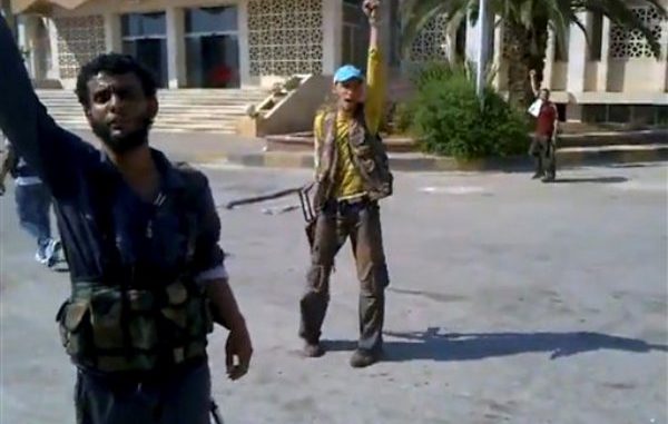 Rebeldes reaccionan mientras un compañero desfigura un cartel con el retrato del presidente Bashar Assad en una imagen captada en un video aficionado por la Red de Noticias Shaam el jueves 19 de julio del 2012 en el pueblo de Bab al-Hawa en el cruce fronterizo con Turquía. Unas 310 personas murieron en toda Siria el jueves, un día considerado como el más cruento de la guerra civil desde que comenzó en una revuelta hace 16 meses, dijeron los activistas sirios el viernes 20 de julio del 2012. (Foto AP/Shaam News Network via video AP)